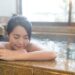 A_woman_rests_beside_a_steaming_indoor_Tokyo_onsen_pool__ - TOKYOwebzine A woman rests beside a steaming indoor Tokyo onsen pool, eyes closed, surrounded by tiled walls and warm mineral water.