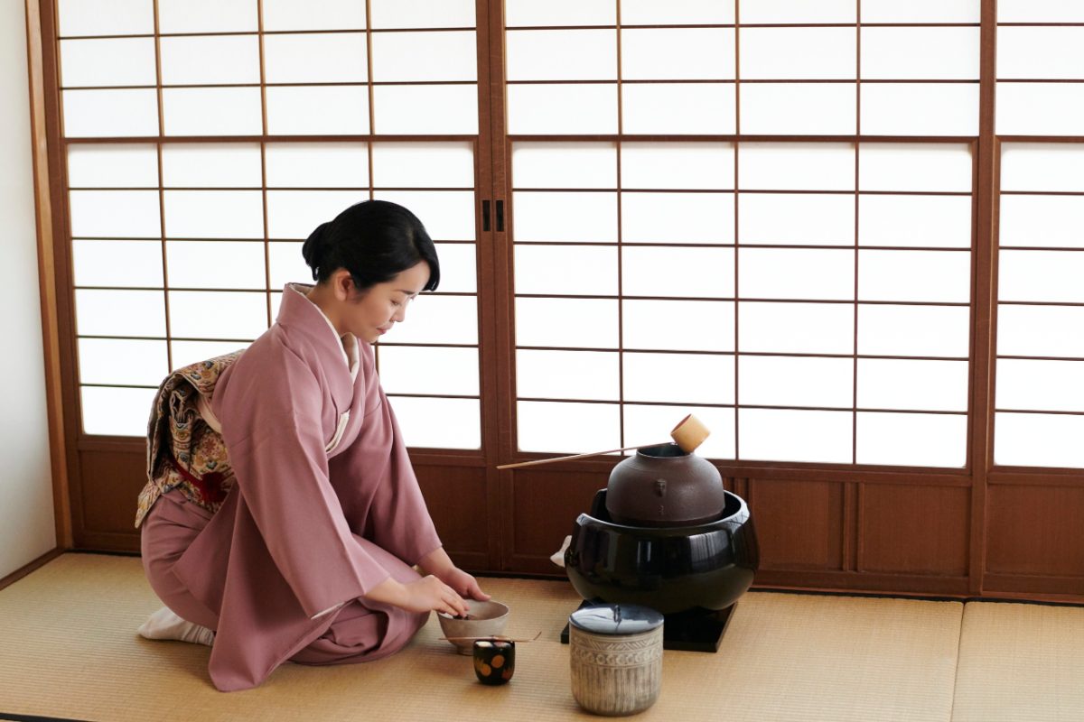 A woman enjoys a traditional tea ceremony indoors in Tokyo during rainy season, embracing the quiet beauty of tsuyu