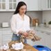 OBE__9_ - TOKYOwebzine A woman carefully practicing trash sorting in a Tokyo apartment kitchen, separating bottles and paper into labeled bins