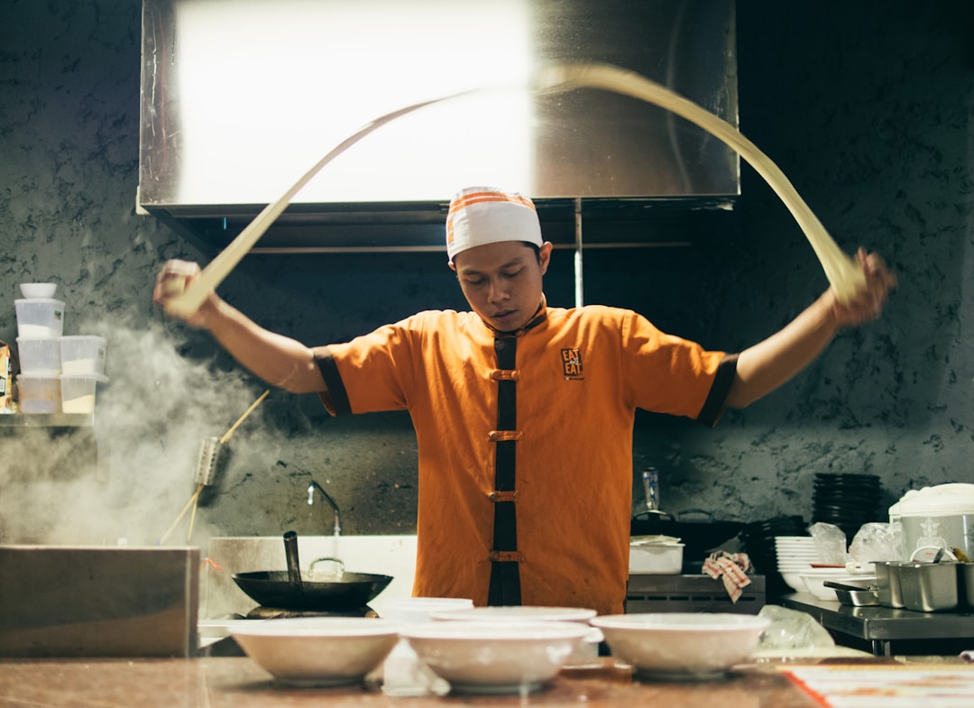A chef in a Tokyo kitchen carefully preparing gluten-free ramen noodles in a dedicated wheat-free kitchen.