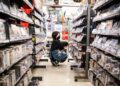 convenience-store-worker-stocking-shelves-japan-unsplash - TOKYOwebzine A konbini culture worker restocking fresh food shelves inside a brightly lit Tokyo convenience store at night