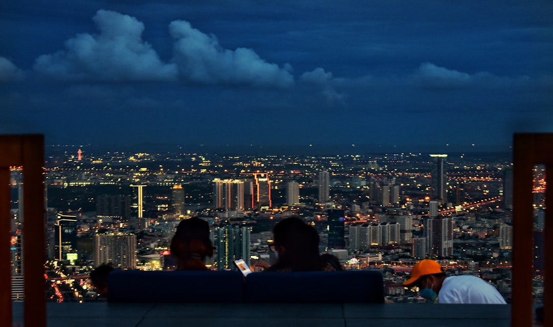 Ein Paar, das in einer Dachbar über Tokio sitzt und Sonnenuntergangs-Cocktails mit einer Panorama-Skyline-Lounge im Hintergrund genießt.