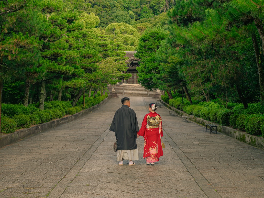 A couple walks a misty temple path surrounded by Tokyo hydrangeas in full bloom during the rainy season.