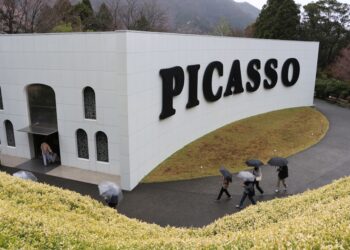 A visitor studying bold color-filled walls at the Picasso exhibition in Tokyo's National Art Center