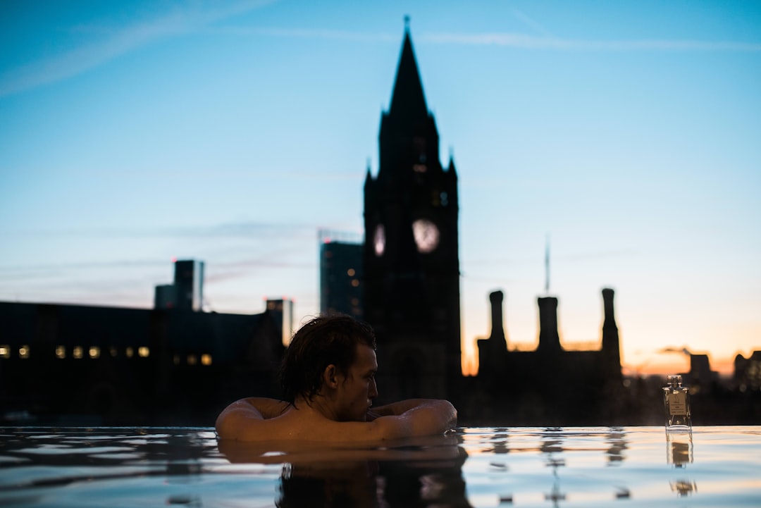 A man soaks in a rooftop outdoor bath at a Tokyo, with city lights reflected on the dark mineral water below a night sky.