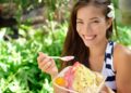A woman savors a bowl of kakigori at aTokyo shop, holding a small spoon over a mountain of shaved ice with fresh fruit syrup.