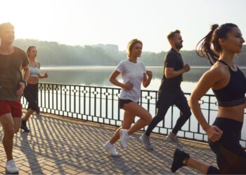 A group of runners at different paces gathering at a Tokyo running club meetup in Yoyogi Park at sunrise