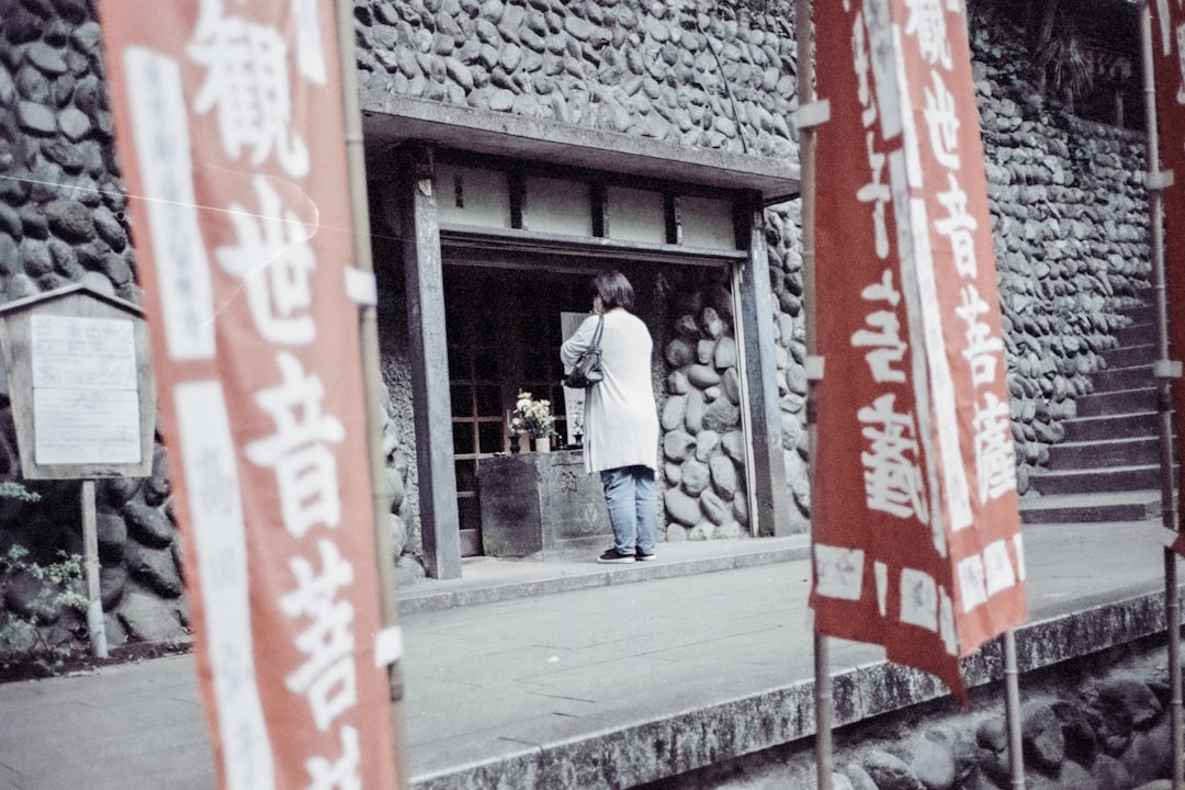 A guest steps through the noren curtain of a neighborhood Tokyo onsen, carrying a small towel and a basket of personal items.