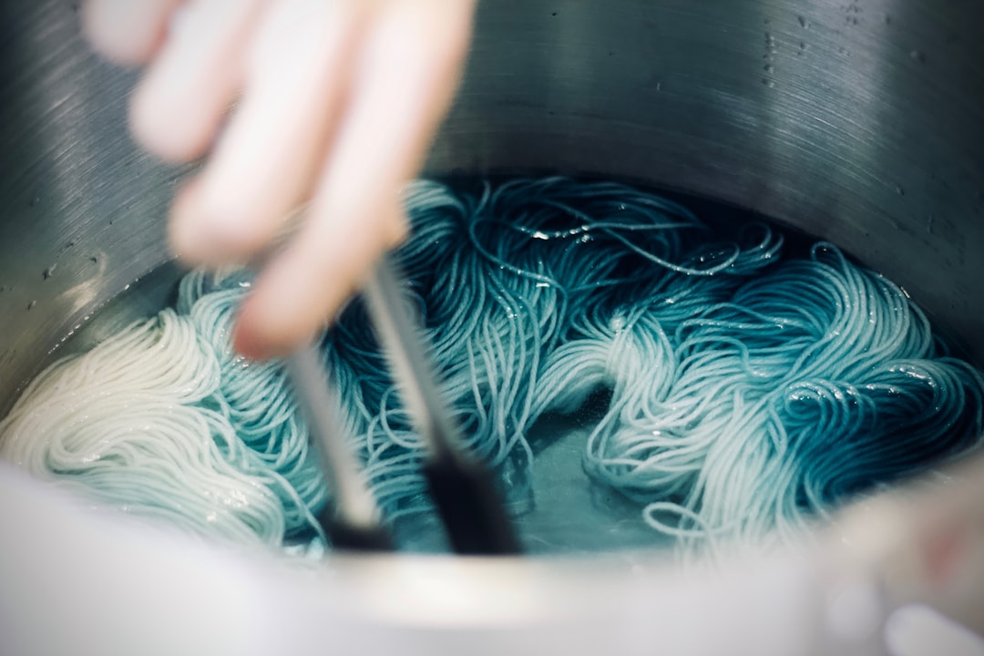 A person lifting indigo-dyed fabric from a vat at a Tokyo workshop, watching the blue color develop