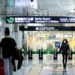 traveller-checking-boarding-pass-airport-japan-unsplash - TOKYOwebzine A traveller reviews their boarding pass at a Tokyo airport departure gate, aware of the departure tax added to their ticket.