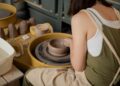 woman-shaping-clay-pottery-wheel-unsplash - TOKYOwebzine A woman shaping clay at a Tokyo workshop pottery wheel, focused and covered in clay dust