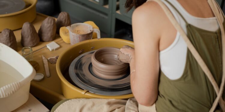 woman-shaping-clay-pottery-wheel-unsplash - TOKYOwebzine A woman shaping clay at a Tokyo workshop pottery wheel, focused and covered in clay dust
