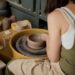 woman-shaping-clay-pottery-wheel-unsplash - TOKYOwebzine A woman shaping clay at a Tokyo workshop pottery wheel, focused and covered in clay dust