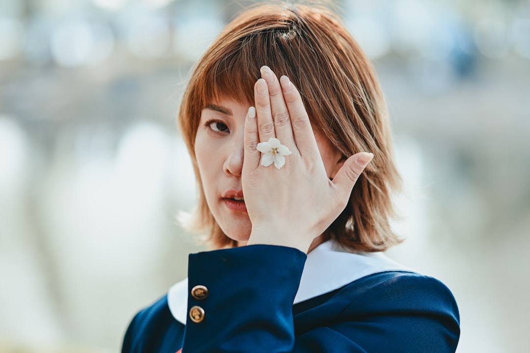 A woman displaying her completed Tokyo nail art, featuring a delicate seasonal motif in soft gel