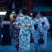 woman-yukata-night-fireworks-crowd-unsplash - TOKYOwebzine A woman in a yukata smiles while watching the Hanabi Tokyo fireworks show at night, surrounded by a crowd of festival-goers.