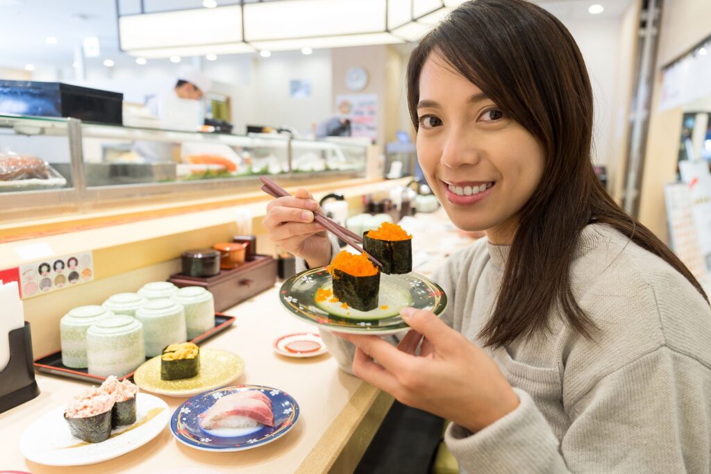 young woman eating sushi in restaurant in Tokyo local guide