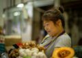 A shopper carefully selecting fresh sashimi trays at a Tokyo depachika basement food hall