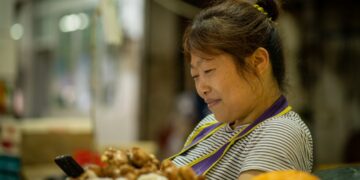 A shopper carefully selecting fresh sashimi trays at a Tokyo depachika basement food hall