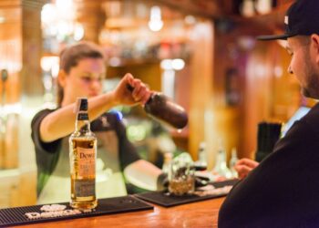A hotel bartender presents a curated Japanese whisky flight on a dark wood counter in Tokyo
