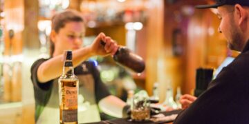 A hotel bartender presents a curated Japanese whisky flight on a dark wood counter in Tokyo