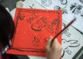 child-painting-traditional-japanese-art-unsplash - TOKYOwebzine A young child concentrates on a brush painting activity during summer kids workshops in Tokyo, surrounded by mineral pigments