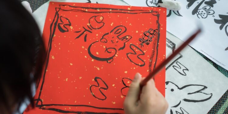 child-painting-traditional-japanese-art-unsplash - TOKYOwebzine A young child concentrates on a brush painting activity during summer kids workshops in Tokyo, surrounded by mineral pigments