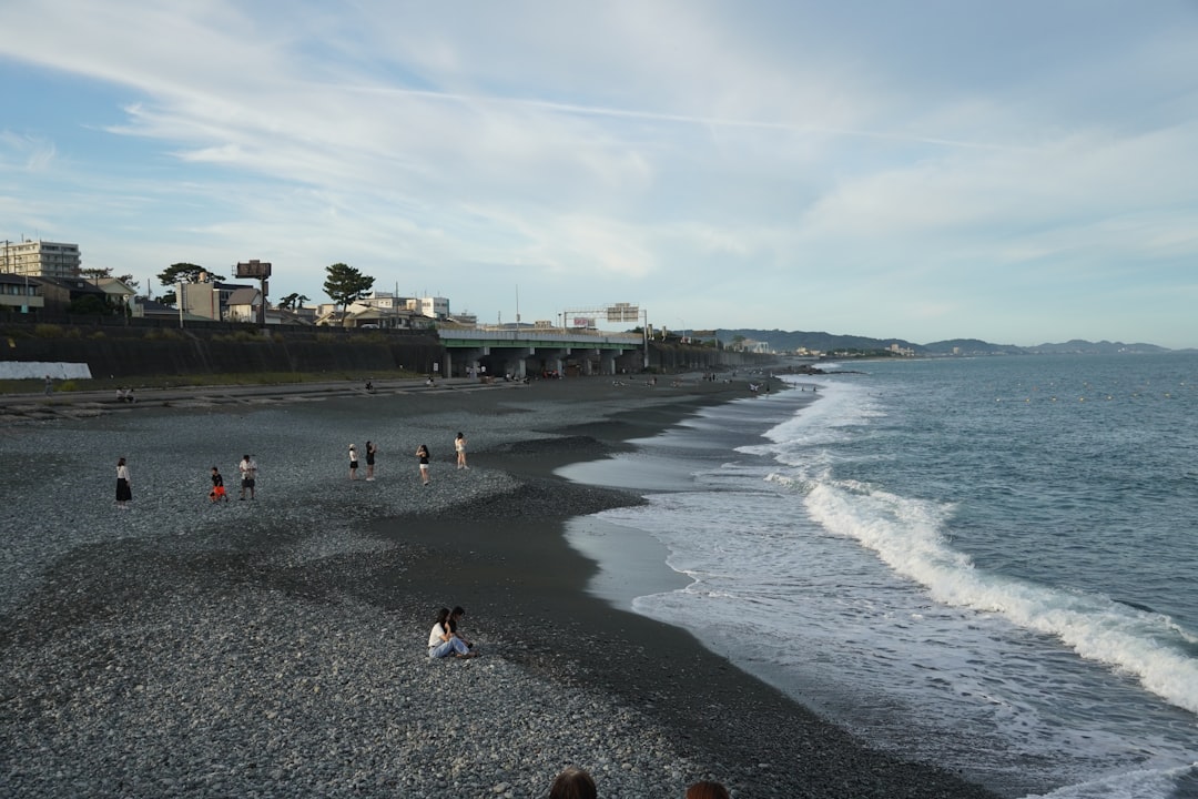 A family sits on the sand at a Tokyo urban beach in Kasai Rinkai Park, enjoying the sea breeze on a humid summer afternoon