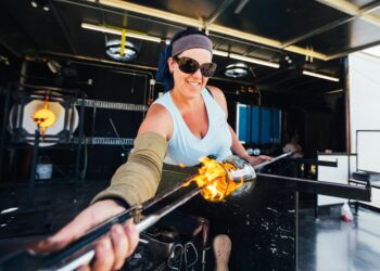 A woman works with molten glass during workshop