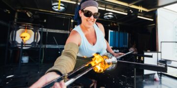 A woman works with molten glass during workshop
