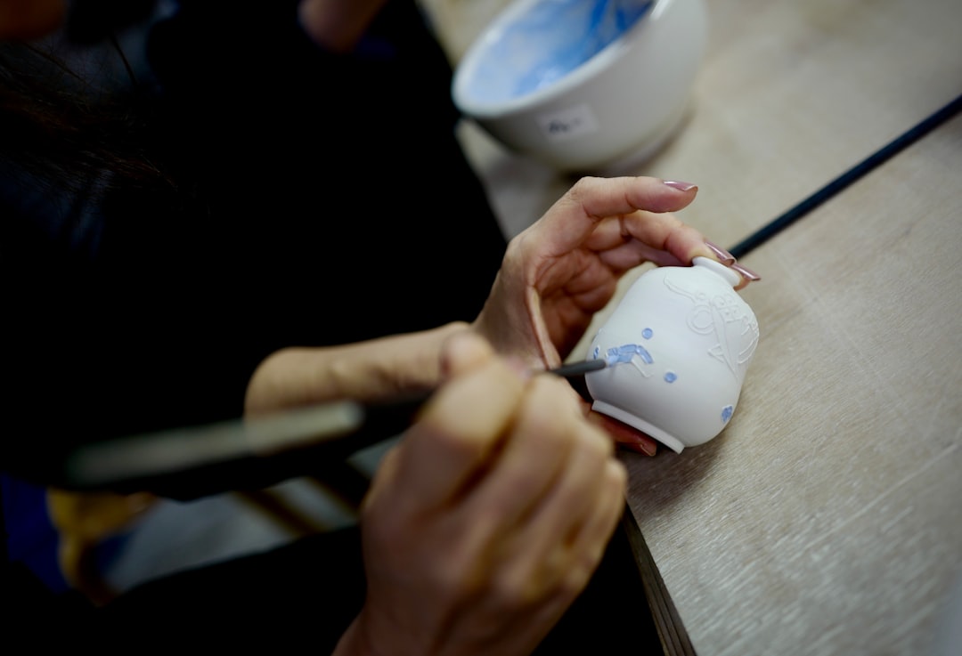 A student applies glaze to a ceramic bowl inside a Tokyo kiln studio, preparing the piece for firing.