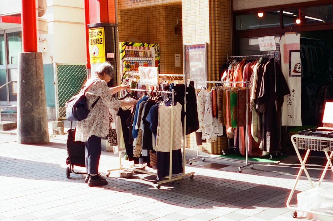 A shopper holds a secondhand jacket on a quiet Tokyo street, reflecting the careful ritual of Tokyo secondhand shopping