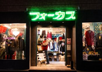 A woman carefully examines natural fibre garments in a Tokyo secondhand wardrobe shop