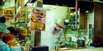 People in a Tokyo soba restaurant, dipping the chilled buckwheat noodles into a ceramic cup of dashi sauce.