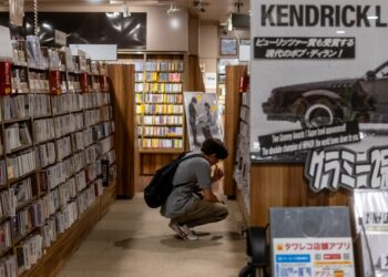 A woman sits quietly in a Tokyo listening bar, experiencing kissa culture through vinyl played on a hi-fi system