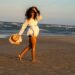 woman-walking-beach-summer-unsplash - TOKYOwebzine A woman walks along one of Tokyo's urban beaches at Odaiba Seaside Park with Rainbow Bridge visible across the water
