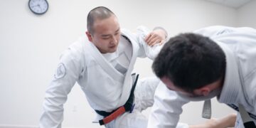 An adult beginner receives English instruction from a sensei at a Tokyo dojo during a karate class