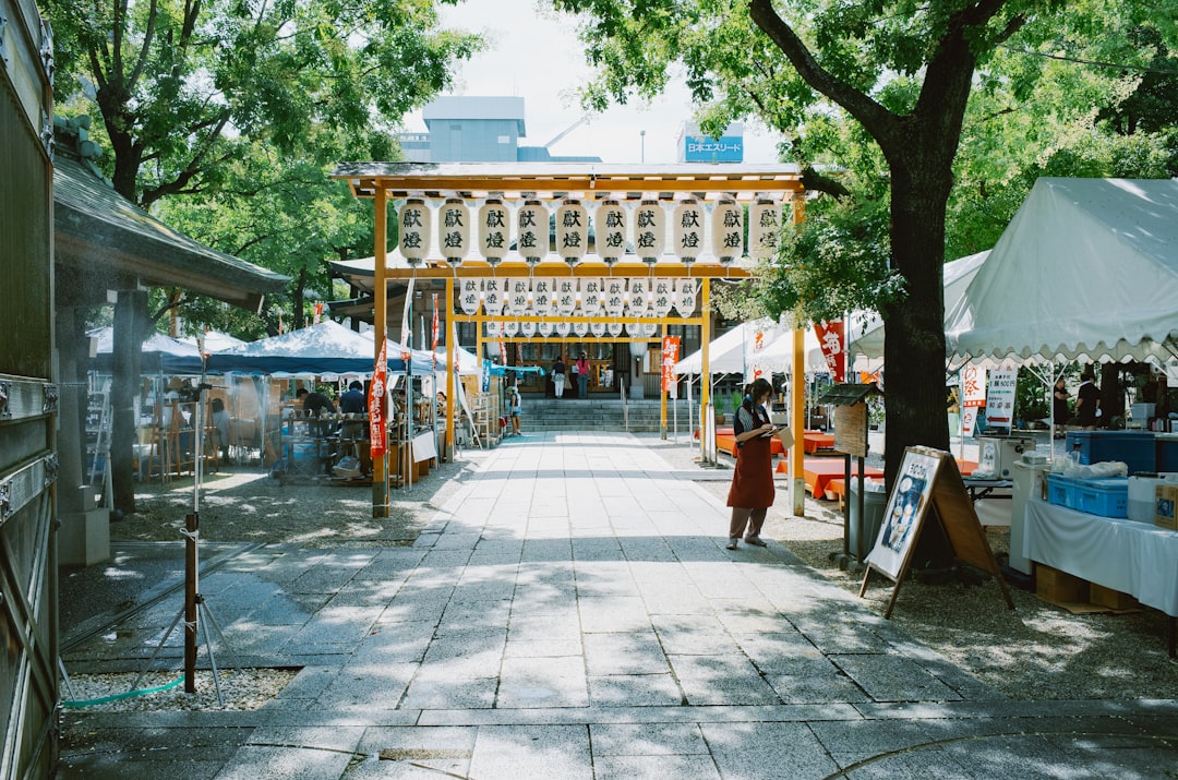 A young artist vendor arranges hand-drawn illustration prints at an open-air art market stall in Tokyo.