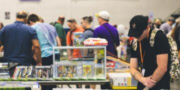 A visitor carefully browsing doujinshi at a Comic Market circle table inside Tokyo Big Sight
