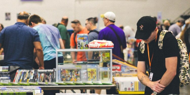 manga-fan-browsing-comics-table-unsplash - TOKYOwebzine A visitor carefully browsing doujinshi at a Comic Market circle table inside Tokyo Big Sight
