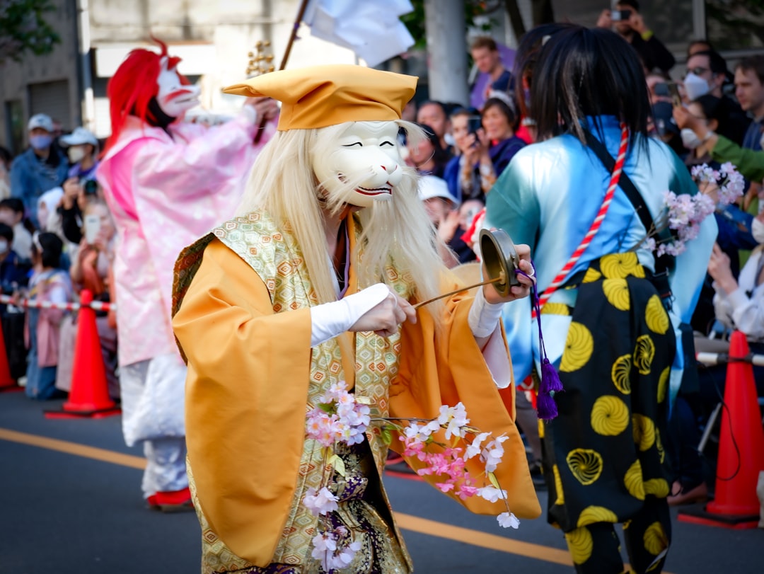 A masked actor mid-movement during outdoor Noh performances in a Tokyo shrine garden setting