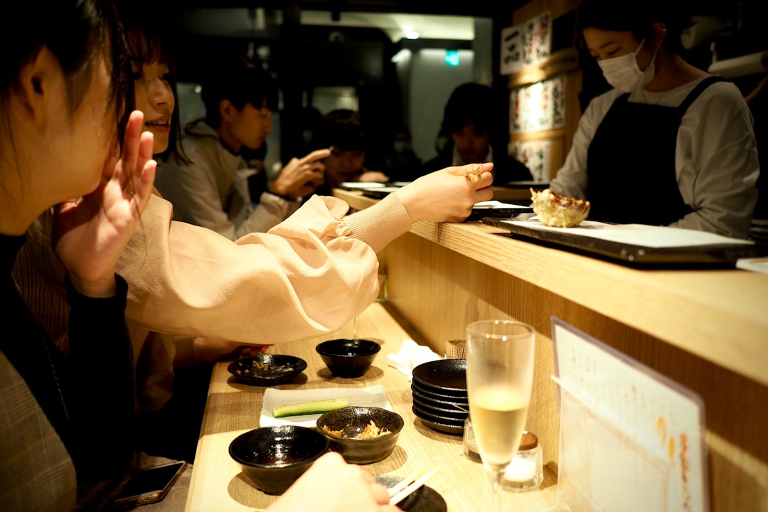 A traveler using a phone app to find a gluten-free izakaya in a Tokyo neighborhood at night