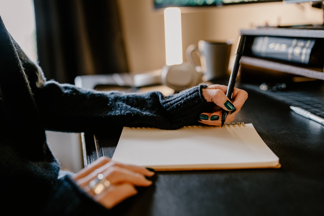 A person writing a detailed brief to send to a custom illustrator, with reference images spread across the desk