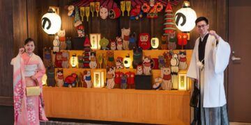 夏の盆休みシーズンに東京の神楽坂旅館入口で着物姿のホストが到着した客を出迎えています。