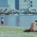 wading into the water at an open water swimming event near Tokyo Bay, with the city skyline visible in the background