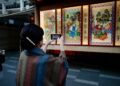 woman-browsing-outdoor-art-stall-tokyo-unsplash - TOKYOwebzine illustration prints displayed on a table at one of the popular art markets in Tokyo on a sunny weekend morning.