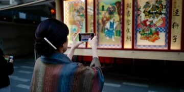 woman-browsing-outdoor-art-stall-tokyo-unsplash - TOKYOwebzine illustration prints displayed on a table at one of the popular art markets in Tokyo on a sunny weekend morning.