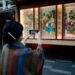 woman-browsing-outdoor-art-stall-tokyo-unsplash - TOKYOwebzine illustration prints displayed on a table at one of the popular art markets in Tokyo on a sunny weekend morning.
