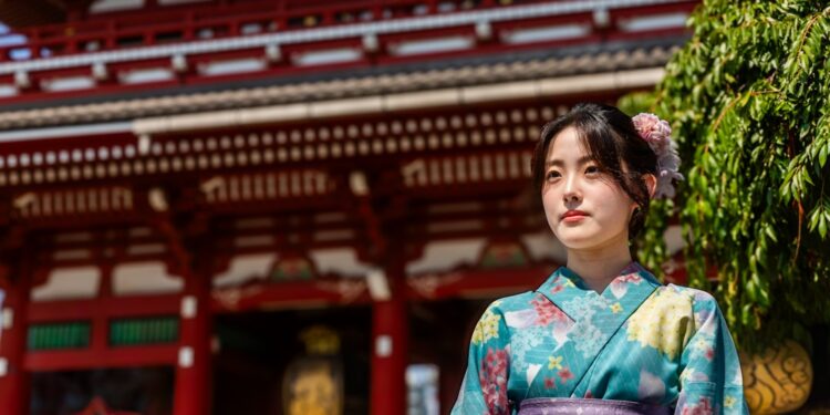 A guest in a yukata robe sits before a Tokyo ryokan kaiseki dinner table set with seasonal dishes and paper lanterns.