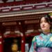 woman-in-yukata-ryokan-dinner-unsplash - TOKYOwebzine A guest in a yukata robe sits before a Tokyo ryokan kaiseki dinner table set with seasonal dishes and paper lanterns.