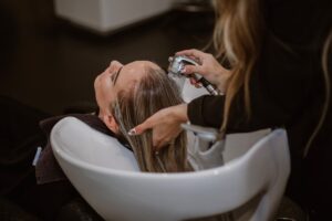 A woman relaxing during a scalp treatment at a Tokyo hair salon, eyes closed as a therapist works gently on her scalp